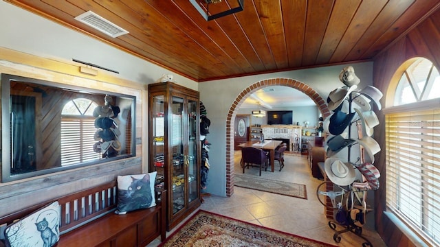 tiled entryway with a fireplace, ornamental molding, and wooden ceiling