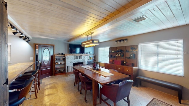 dining area with rail lighting, a brick fireplace, and wood ceiling