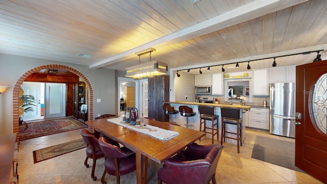 dining space featuring beam ceiling, rail lighting, wooden ceiling, and light tile patterned floors