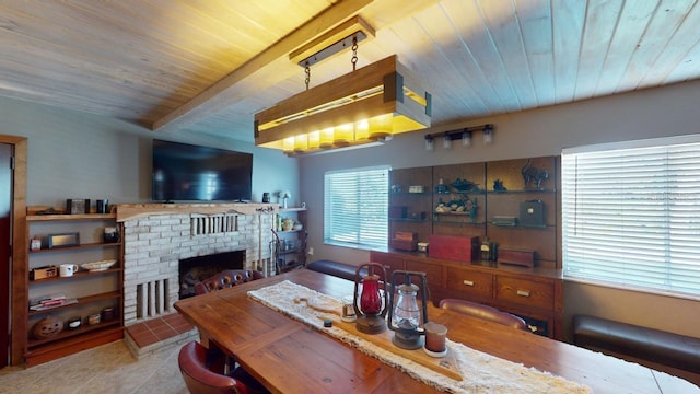 tiled dining space with beam ceiling, a brick fireplace, and wooden ceiling