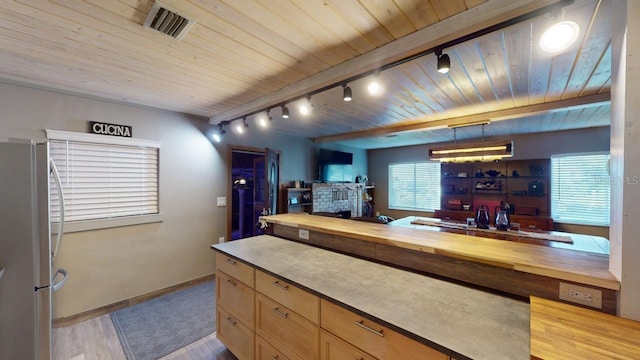 bar featuring stainless steel fridge, rail lighting, decorative light fixtures, light hardwood / wood-style flooring, and butcher block countertops