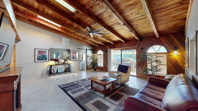 tiled living room featuring vaulted ceiling with skylight, wood ceiling, ceiling fan, a barn door, and wood walls