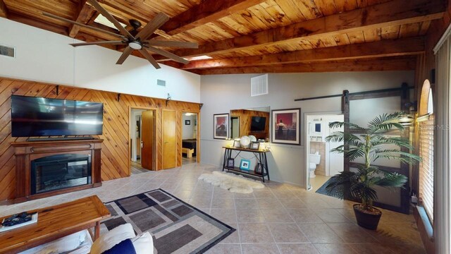 living room featuring beam ceiling, ceiling fan, a barn door, high vaulted ceiling, and light tile patterned flooring