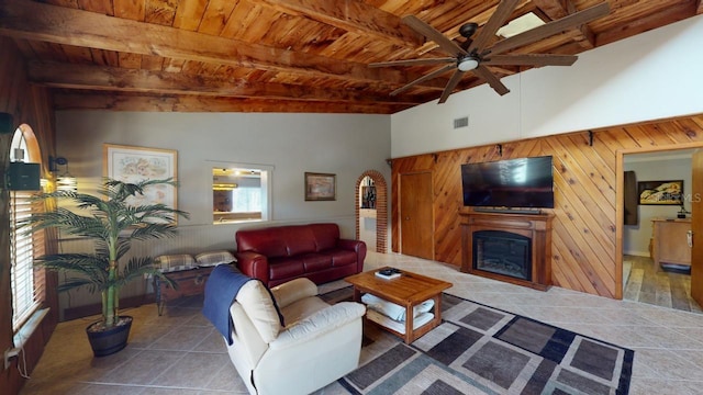 living room featuring beam ceiling, ceiling fan, tile patterned floors, wood walls, and wood ceiling