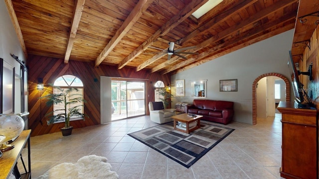 living room featuring wooden ceiling, lofted ceiling with beams, wooden walls, ceiling fan, and light tile patterned flooring