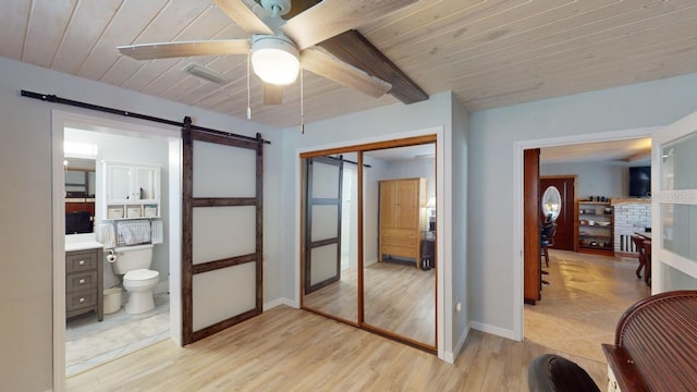 bedroom with a barn door, a closet, ceiling fan, and wooden ceiling