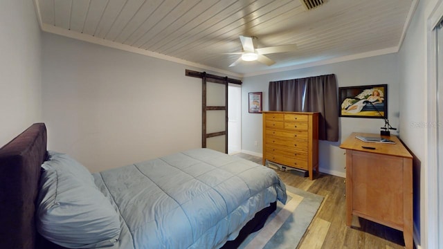 bedroom with ceiling fan, a barn door, ornamental molding, and light hardwood / wood-style flooring