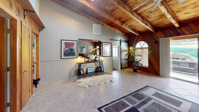 tiled entryway featuring a barn door, wood walls, wooden ceiling, and vaulted ceiling with beams