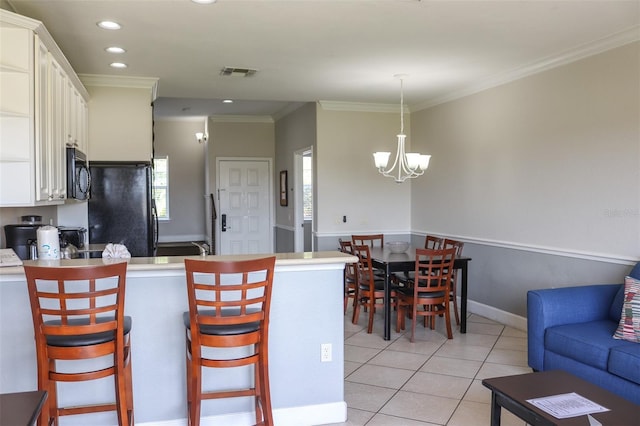 kitchen with crown molding, black appliances, decorative light fixtures, white cabinets, and a chandelier