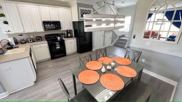 kitchen with black appliances, crown molding, white cabinets, and sink