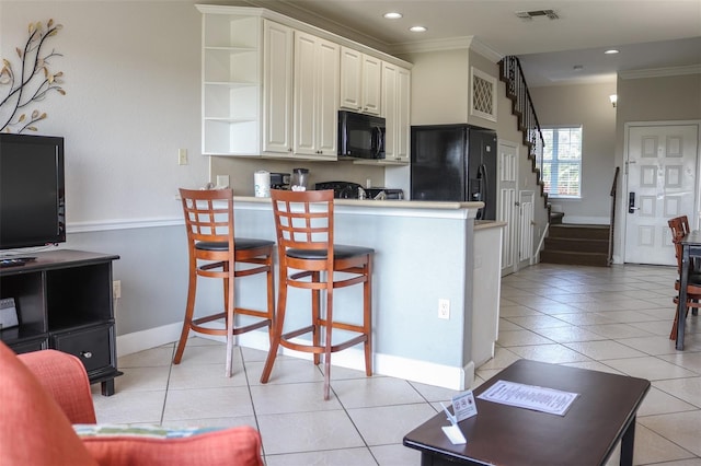 kitchen with a breakfast bar, black appliances, crown molding, kitchen peninsula, and white cabinetry