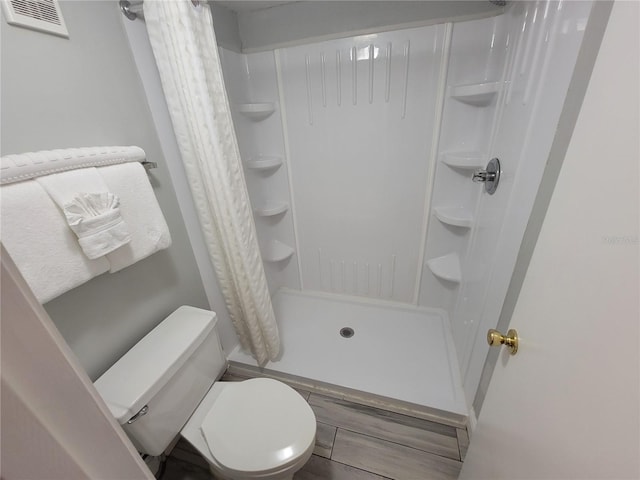 bathroom with walk in shower, toilet, and hardwood / wood-style flooring