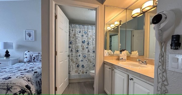 bathroom with a textured ceiling, vanity, wood-type flooring, toilet, and curtained shower