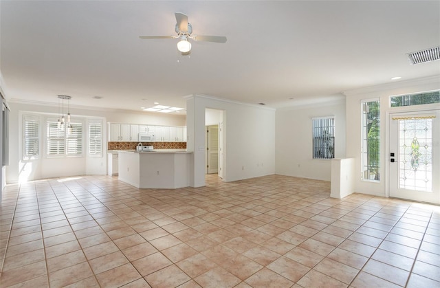 unfurnished living room with light tile patterned floors, a wealth of natural light, and ornamental molding