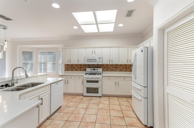 kitchen featuring white appliances, white cabinetry, sink, hanging light fixtures, and light tile patterned flooring