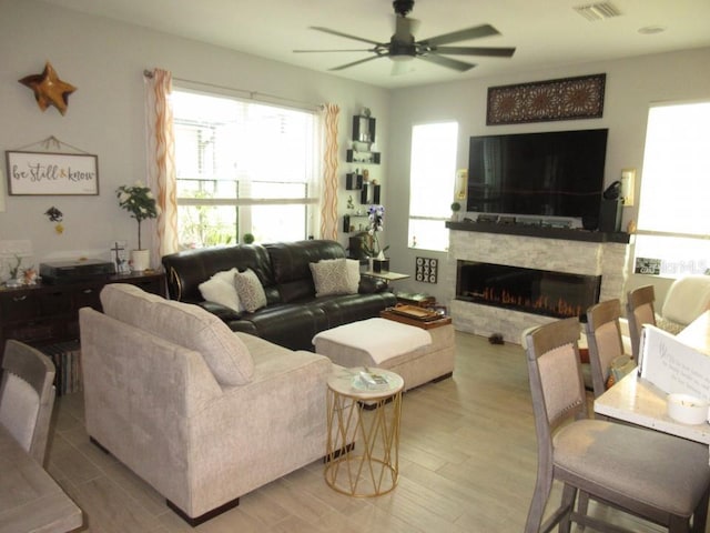 living room with ceiling fan, a fireplace, and light hardwood / wood-style flooring