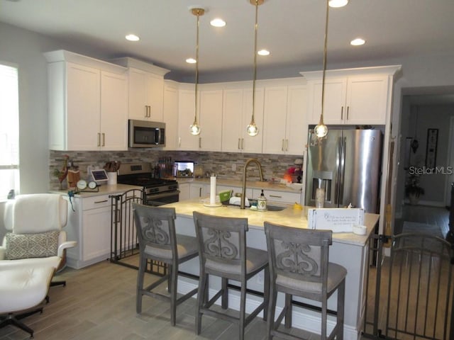 kitchen featuring sink, white cabinetry, hanging light fixtures, appliances with stainless steel finishes, and backsplash