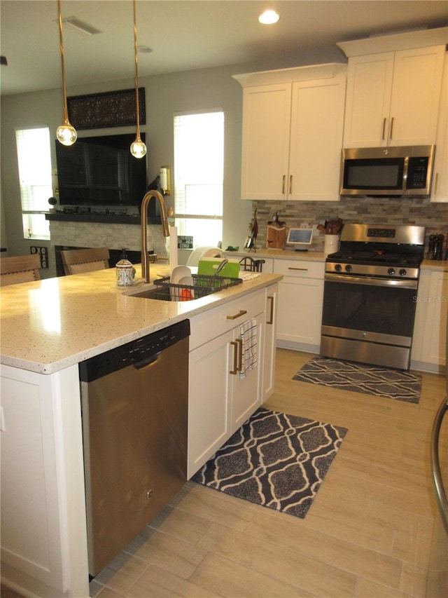 kitchen featuring white cabinetry, appliances with stainless steel finishes, sink, and pendant lighting