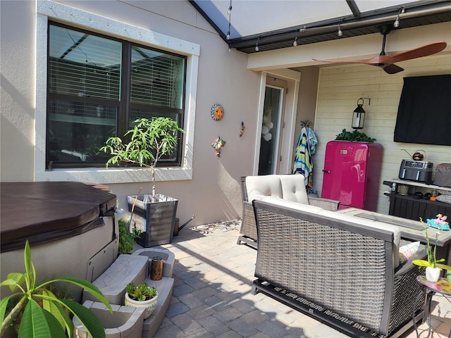 view of patio with a hot tub, an outdoor living space, and ceiling fan