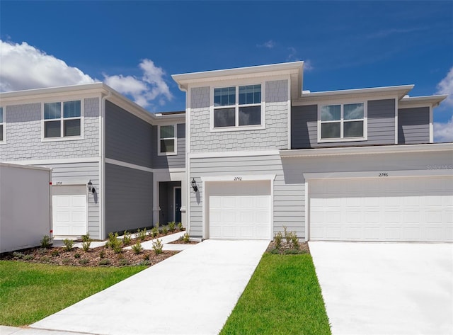 multi unit property featuring a garage and concrete driveway