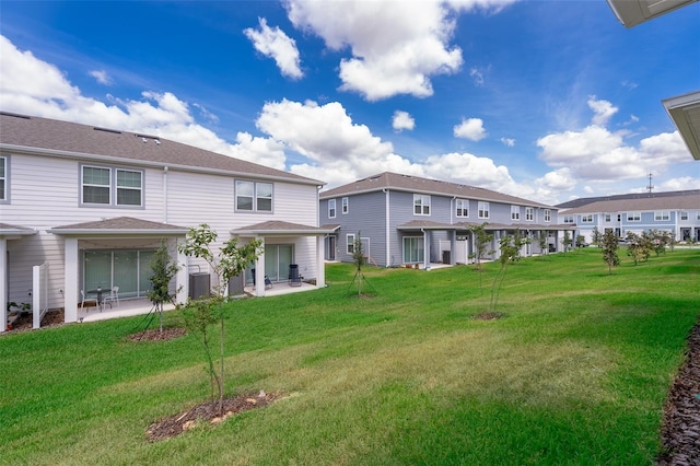 back of property with a yard, central AC, a patio area, and a residential view