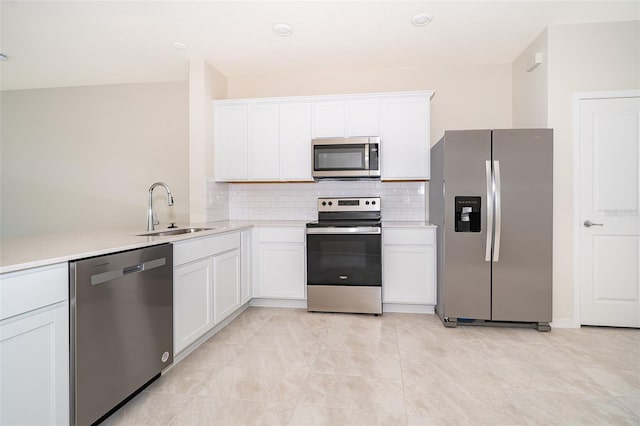 kitchen with stainless steel appliances, a sink, white cabinets, light countertops, and decorative backsplash