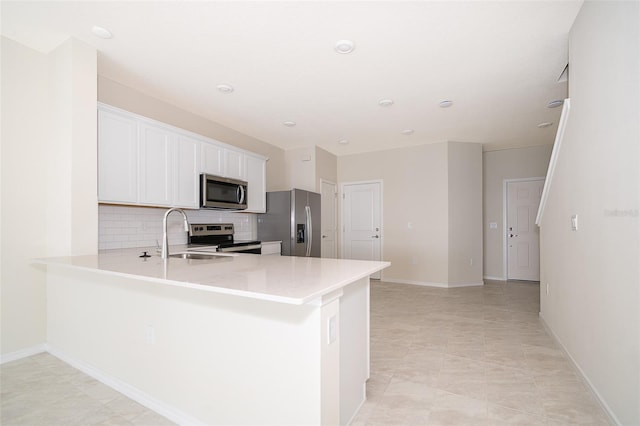 kitchen featuring tasteful backsplash, light countertops, appliances with stainless steel finishes, white cabinets, and a sink