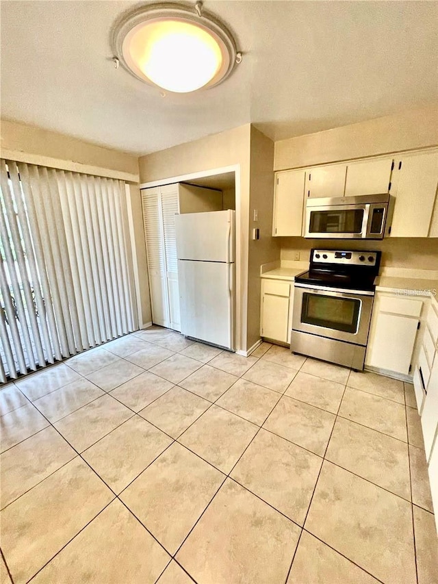 kitchen with white cabinets, appliances with stainless steel finishes, a textured ceiling, and light tile patterned flooring