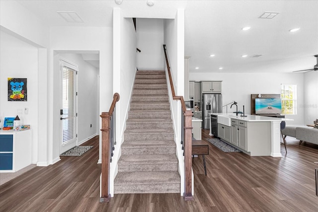 staircase with hardwood / wood-style flooring, ceiling fan, and sink