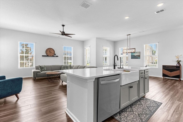 kitchen featuring dark hardwood / wood-style flooring, a wealth of natural light, dishwasher, and a center island with sink