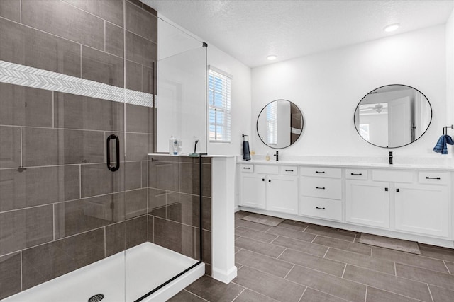 bathroom with a textured ceiling, vanity, and walk in shower