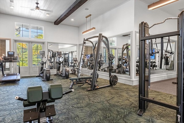 exercise room with carpet flooring, ceiling fan, and a towering ceiling