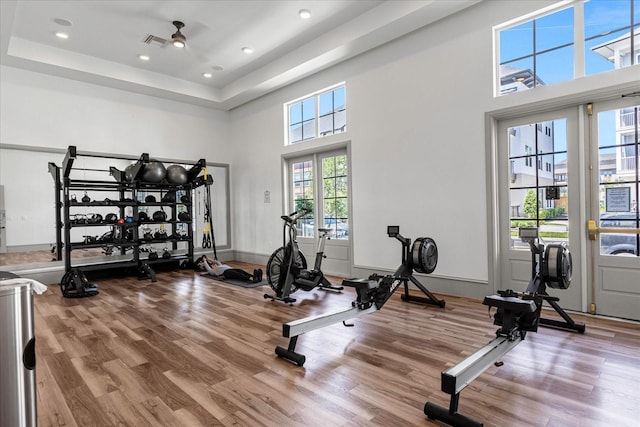 exercise room with hardwood / wood-style flooring, ceiling fan, and a high ceiling