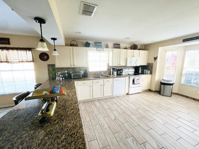 kitchen with pendant lighting, white appliances, white cabinets, backsplash, and sink