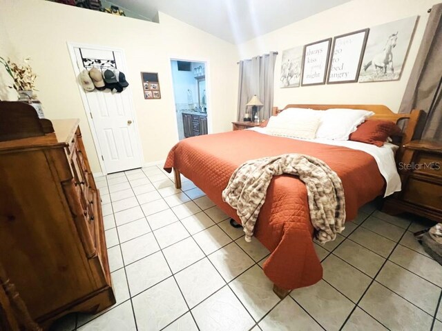 bedroom featuring connected bathroom, vaulted ceiling, and light tile patterned floors