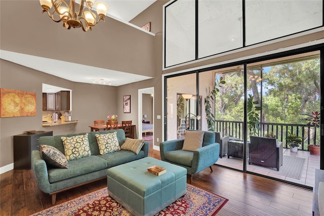 living room with hardwood / wood-style floors, a notable chandelier, and a towering ceiling