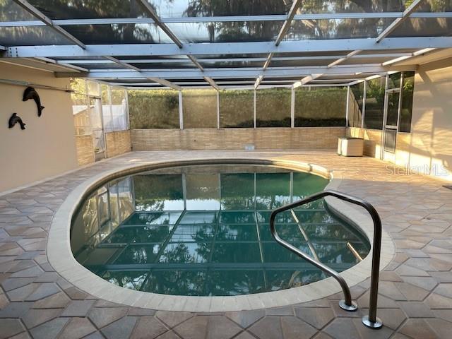 view of pool with glass enclosure and a patio