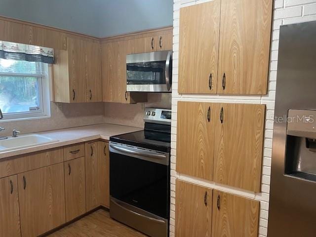 kitchen featuring sink, light wood-type flooring, light brown cabinets, and appliances with stainless steel finishes