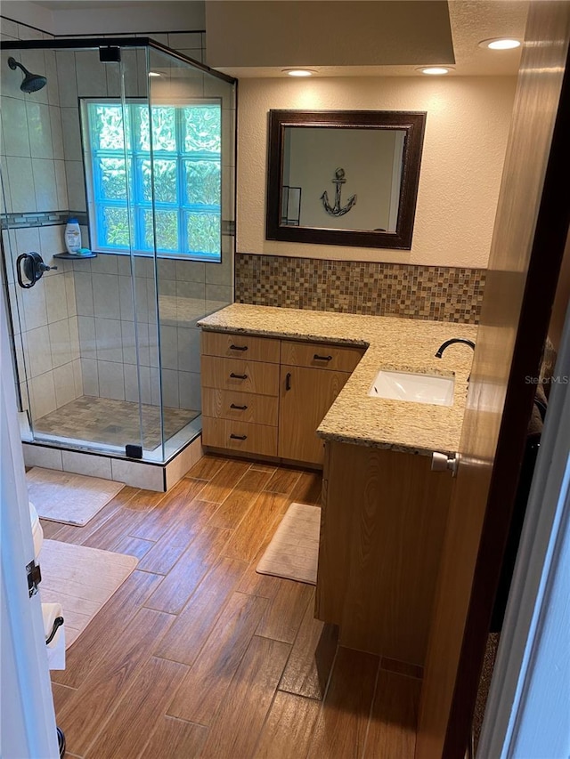 bathroom with decorative backsplash, vanity, and an enclosed shower