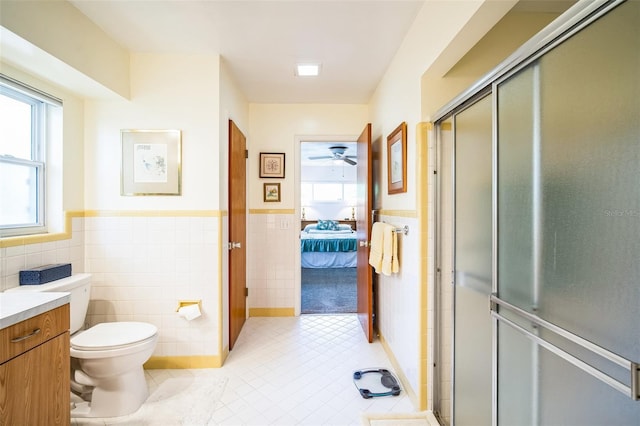 3240 San Mateo St, Clearwater, FL 33759 - ensuite bathroom featuring tile walls, a wainscoted wall, ceiling fan, a stall shower, and tile patterned floors