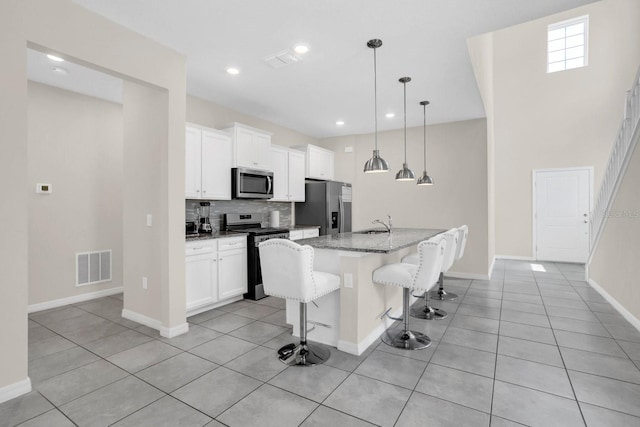 kitchen with stainless steel appliances, tasteful backsplash, a kitchen island with sink, and white cabinetry