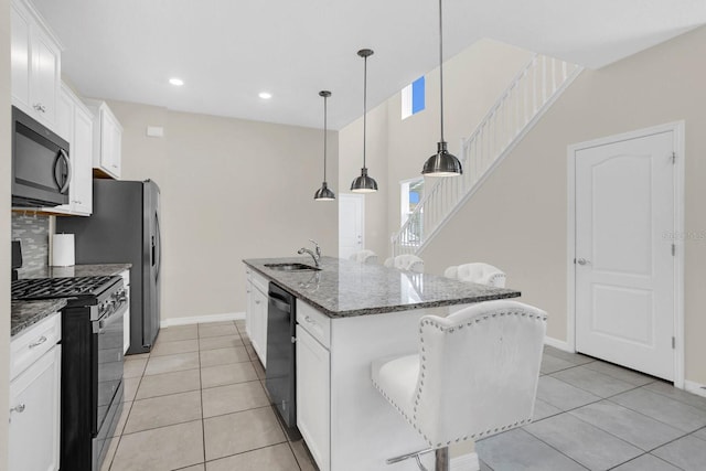 kitchen with gas range, hanging light fixtures, sink, a kitchen island with sink, and white cabinetry