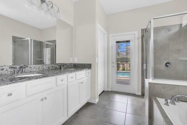 bathroom featuring tile flooring, independent shower and bath, vanity with extensive cabinet space, and dual sinks