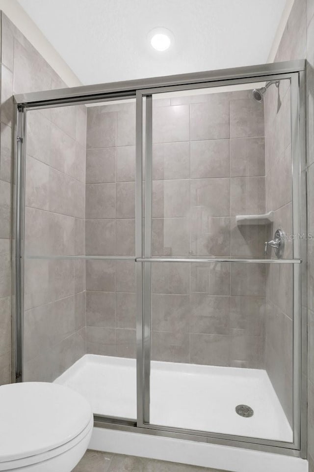 bathroom featuring a shower with shower door and toilet