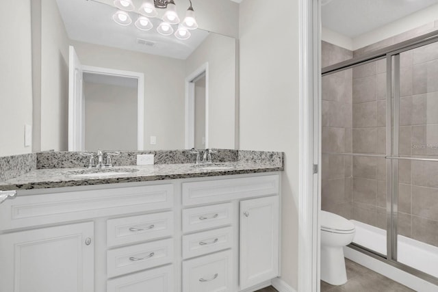 bathroom featuring dual vanity, walk in shower, and toilet