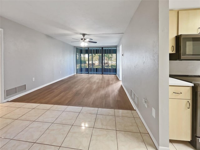 unfurnished room featuring ceiling fan, floor to ceiling windows, and light hardwood / wood-style flooring