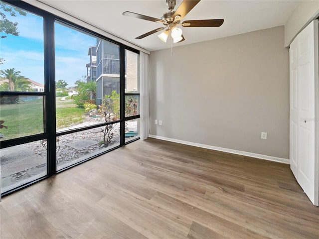 spare room with floor to ceiling windows, ceiling fan, and hardwood / wood-style floors