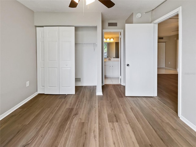 unfurnished bedroom with connected bathroom, ceiling fan, a closet, and hardwood / wood-style flooring