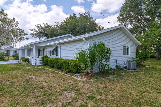 view of home's exterior with central AC unit, covered porch, and a yard