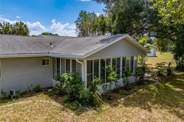 back of property with a lawn and a sunroom